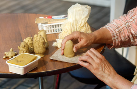 Person is making a clay sculpture on a table. There are several other clay sculptures on the tableの写真素材