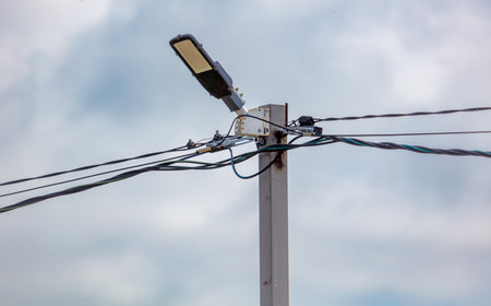 A street light is on a pole with wires coming out of it. The sky is cloudy and the light is onの写真素材