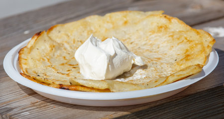 A plate of pancakes with whipped cream on top. The pancakes are golden brown and the whipped cream is spread evenly on topの写真素材