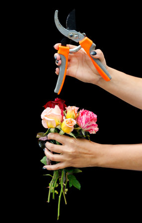 A person holding a bouquet of flowers with a pair of scissors. The scissors are orange and black