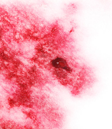 A red stain on a white surface. The stain is large and has a dark red color. The surface is covered...