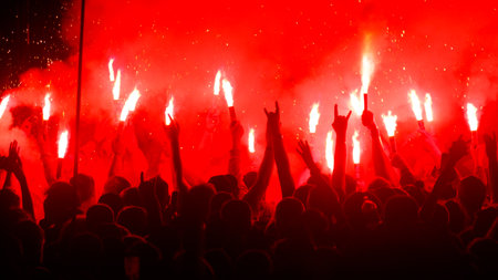 A crowd of people are holding red lit torches and are cheering. Scene is energetic and celebratoryの写真素材
