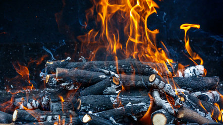 A pile of wood is burning, with the flames reaching high into the air. Concept of warmth and coziness, as well as the natural process of combustionの写真素材