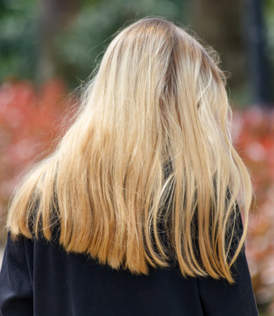 A blonde woman with long hair is walking in a park. The hair is slightly damaged and dryの写真素材