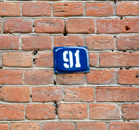 A blue and white sign with the number 91 on it. The sign is attached to a brick wallの写真素材