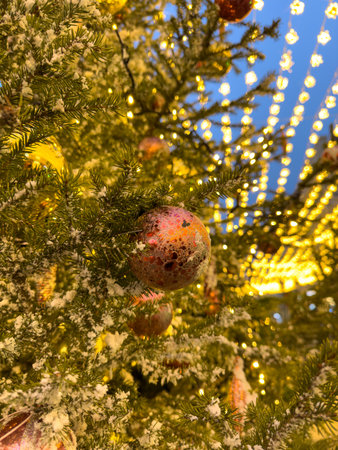 A Christmas tree with many ornaments on it. A red ball is hanging from the treeの写真素材