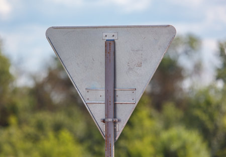 A triangular sign with a white arrow pointing to the right. The sign is rusted and has a black writing on itの写真素材