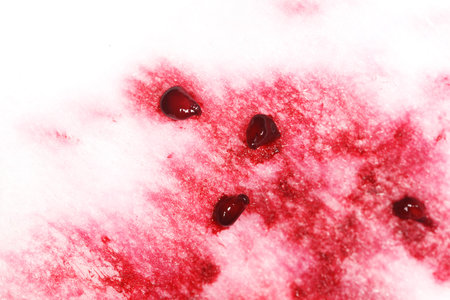 A close up of a red stain on a white surface. The stain is made up of small red dots. The red dots may be paint or another liquid.の写真素材