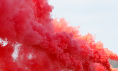 A red cloud of smoke is billowing into the sky. The smoke is thick and dense, creating a sense of chaos and destruction. The red color of the smoke is striking and intenseの写真素材