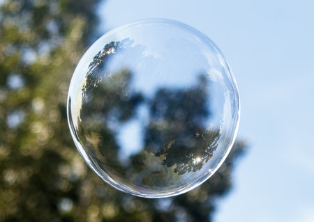 Bubble is floating in the air. The bubble is clear and round. The sky is blue and the sun is shiningの写真素材