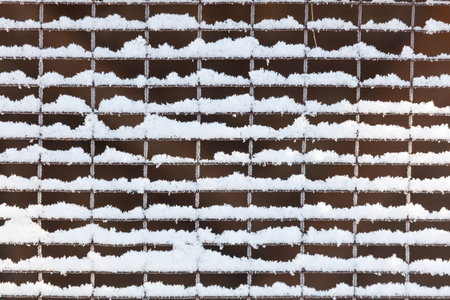A wall covered in snow. The snow is piled up in the middle of the wall. The snow is white and fluffyの写真素材