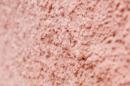 A wall with a pinkish color. The wall is made of cement. There is a crack in the wall