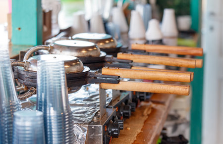 A waffle iron with three waffle irons on top of it. There are also three wooden handles on the...