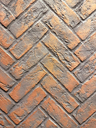 A brick wall with a chevron pattern. The bricks are brown and grayの写真素材