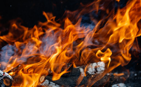 A close up of a fire with flames reaching up to the sky. The fire is surrounded by wood, and the...