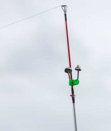 A green and white object is attached to a white pole. The pole is attached to a rope, which is...
