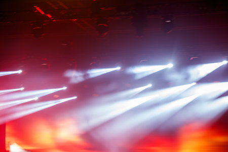 A stage with lights shining on it. The lights are white and red. The stage is set for a concert