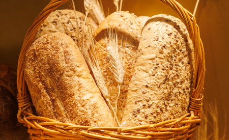 A basket of bread with a few pieces of wheat in it. The bread is brown and the wheat is white