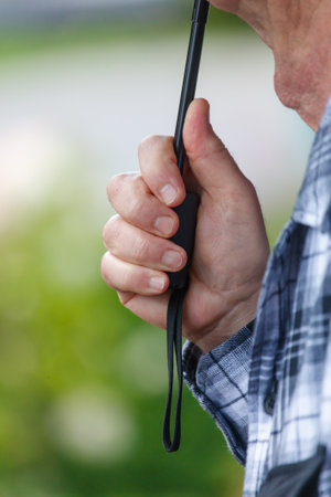 A man holding a black umbrella. The umbrella is black and has a black handle. The man is holding the...