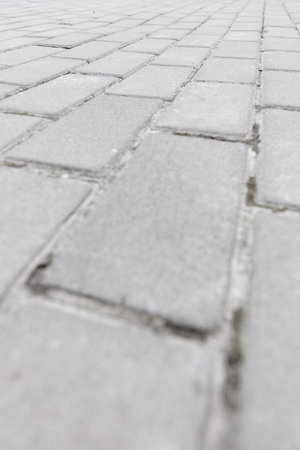 A close up of a brick sidewalk. The bricks are white and the sidewalk is grey. The bricks are laid...