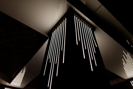 A black pole with a series of lights on it. The lights are arranged in a line. The pole is lit up
