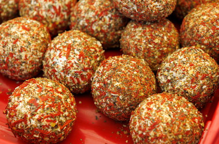 A red tray with many small balls of food on it. The balls are covered in spices and are of different...