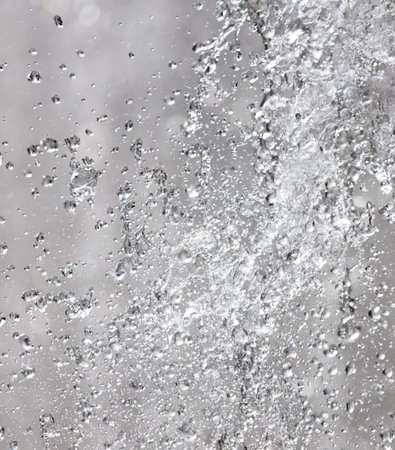 A spray of water droplets on a white background. The water droplets are scattered and appear to be falling from a heightの写真素材