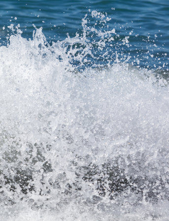 A wave in the ocean with white foam. The foam is white and the water is blue. The wave is crashing and the foam is being pushed out of the waterの写真素材