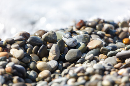 A pile of rocks on the beach. The rocks are of different sizes and colors. Some are gray, some are black, and some are brownの写真素材