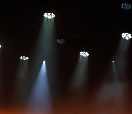 The room is filled with bright lights, creating a warm and inviting atmosphere. The lights are positioned at various heights and angles, casting a soft glow over the space. The room is dimly litの写真素材
