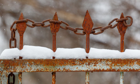 A chain link fence with a chain hanging from it. The chain is rusty and has four linksの写真素材