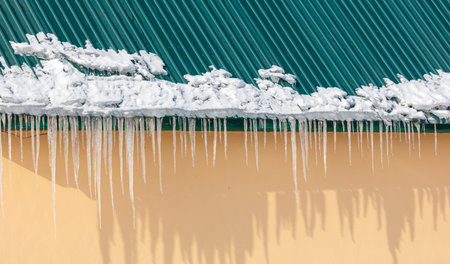 Icicles hanging from a roof. The icicles are long and thinの写真素材