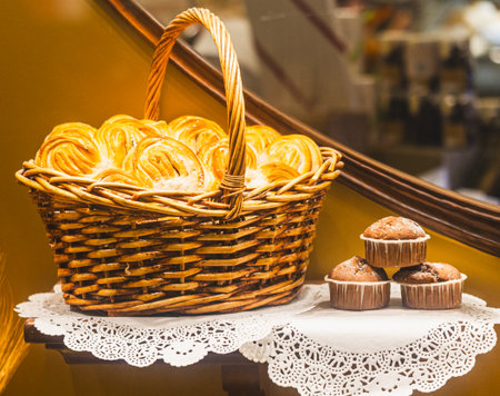 A basket filled with a variety of pastries and muffins is placed on a table. The pastries include croissants, danishes, and other sweet treatsの写真素材
