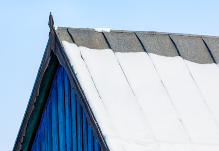 A blue roof with snow on it. The roof is slanted. The snow is whiteの写真素材