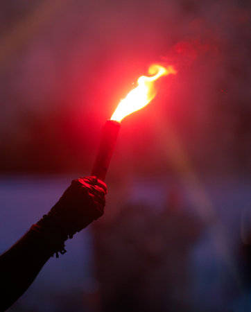 A person holding a red lit candle. The candle is lit and the flame is very brightの写真素材