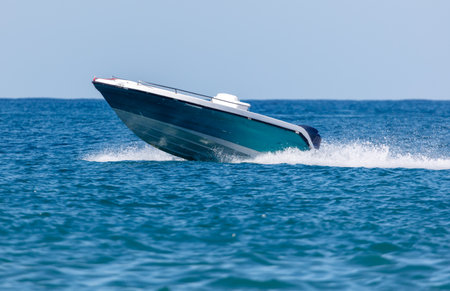 A small blue boat is in the water. The boat is moving fast