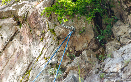 Blue rope is tied to a rock. The rope is attached to a chain