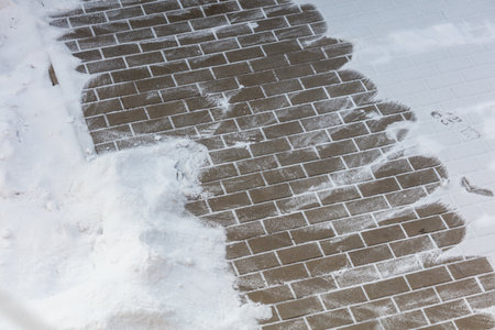 A brick walkway covered in snow. The snow is piled up on the bricksの写真素材