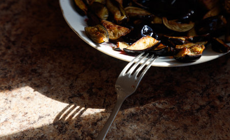 A fork is on a plate with vegetables. The fork is bent at the tinesの写真素材
