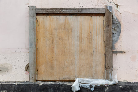 A wooden door with a hole in it. The door is closed and the wall is covered in paintの写真素材