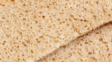 A slice of bread with holes in it. The bread is brown and has a crust. The bread is cut in half