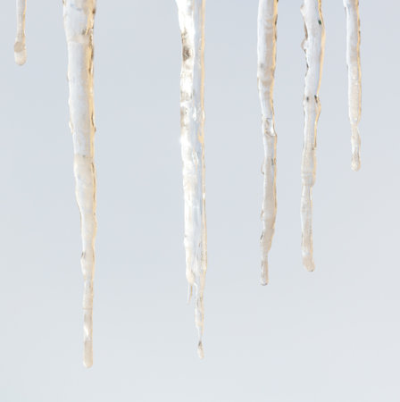 A series of icicles hanging from a roof. The icicles are long and thin. They are white and appear to be frozenの写真素材