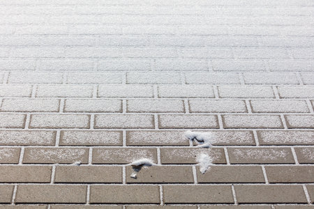 A brick wall covered in snow. The snow is piled up on the bricks. There is a foot print in the snowの写真素材