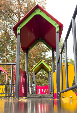 A playground with a red and green house. The house is on the left side of the playgroundの写真素材