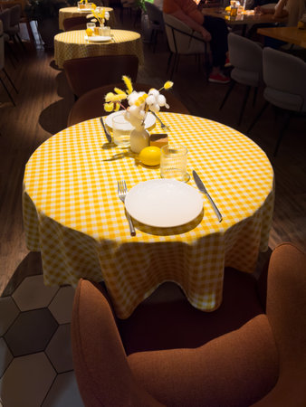A table with a yellow checkered tablecloth and a white plate with a fork and knife on itの写真素材