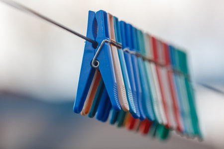 A bunch of colorful clothespins are hanging on a line. The clothespins are blue, red, and green, and...
