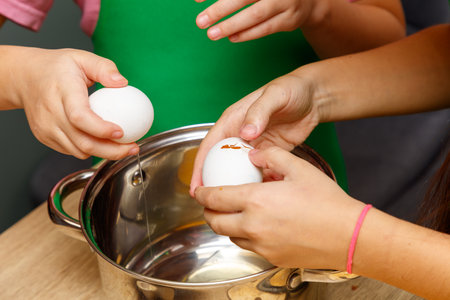 Two women are cracking eggs into a bowl.の写真素材
