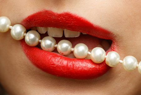 A woman's mouth is covered with a string of pearls. The pearls are in the shape of a necklaceの写真素材