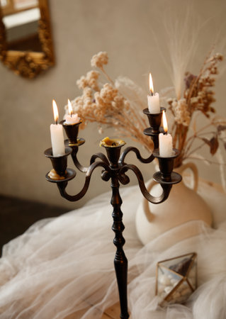 A tall candle holder with five candles in it. The candles are lit and are in the middle of a tableの写真素材