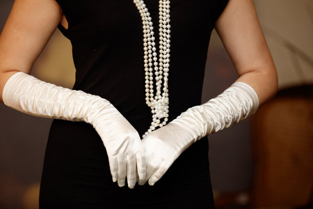 A woman wearing a black dress and white gloves. She is holding her hands upの写真素材